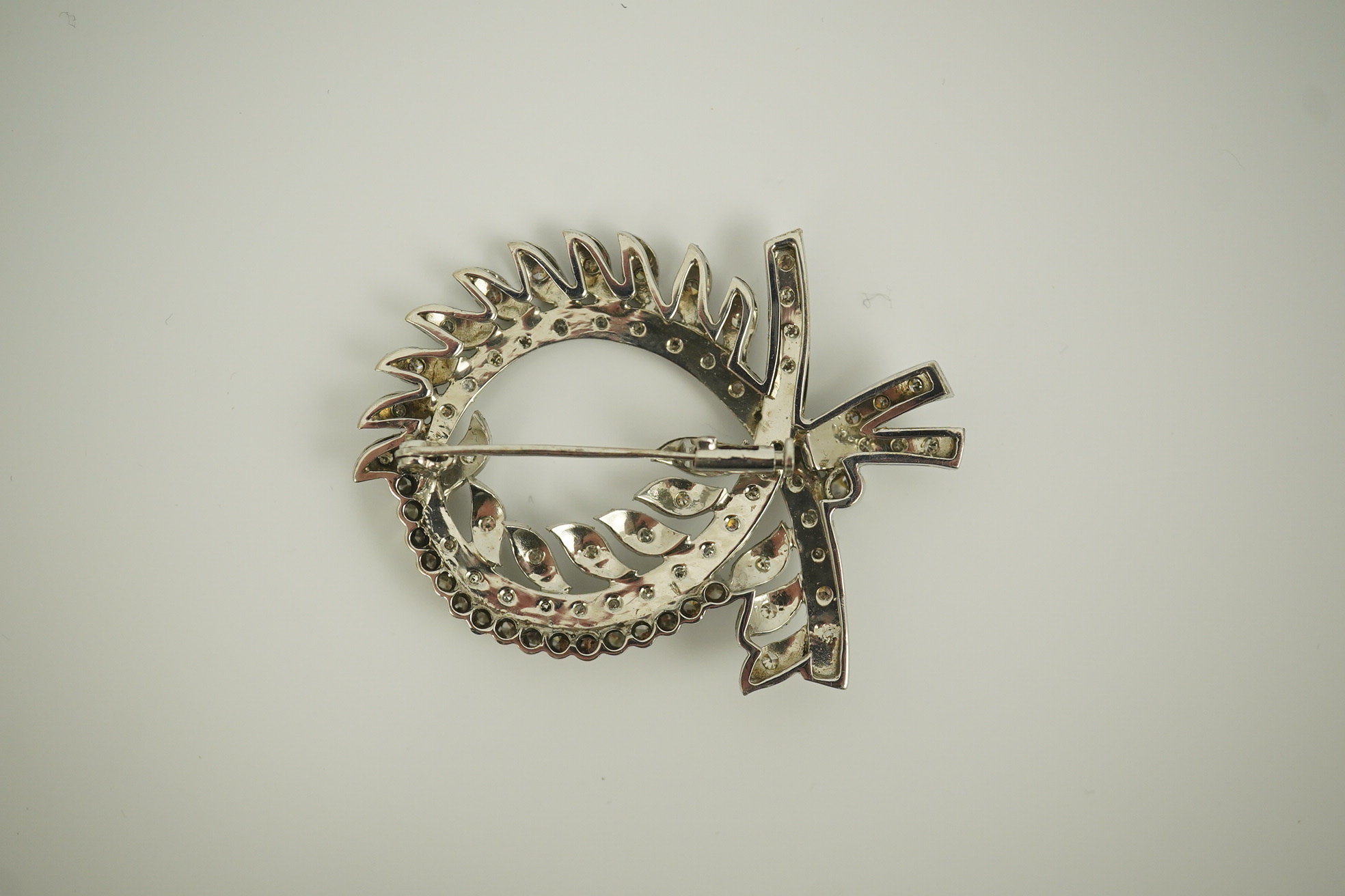 A recent white gold and diamond cluster set scrolling wreath brooch